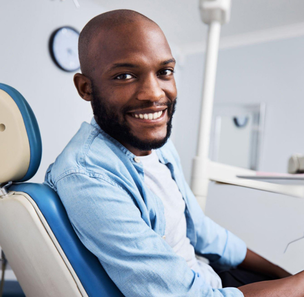 Smiling man in dental chair wearing light blue shirt at Dove Family Dentistry office
