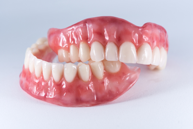 Dental prosthetic model displaying full upper and lower dentures with realistic teeth arrangement against white background.