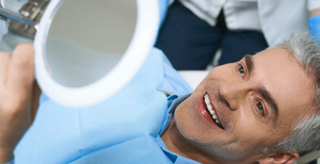 Man smiling at dental mirror during checkup at Dove Family Dentistry office.
