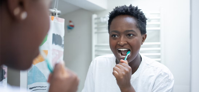 Woman brushing teeth at bathroom mirror in modern dental care setting