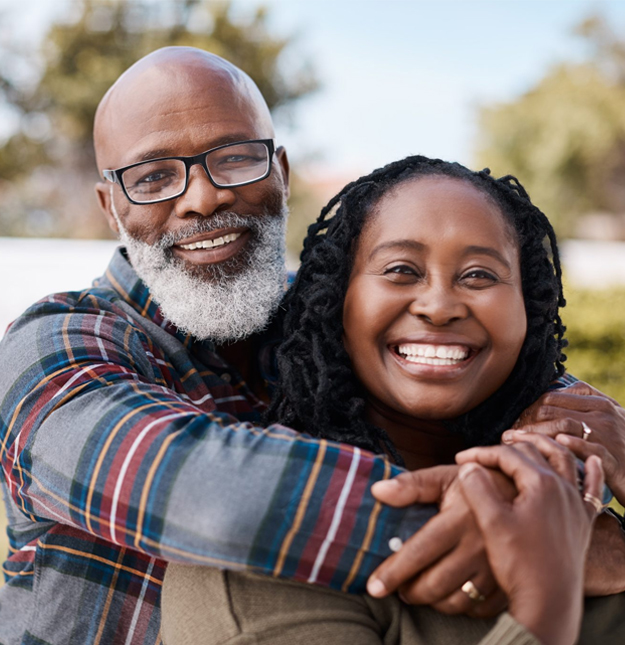 Smiling father and daughter embracing outdoors in natural daylight, promoting family dental care.