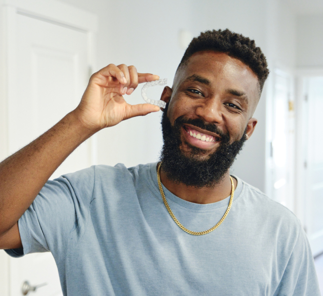 Man smiling while holding dental floss in a bright bathroom setting.