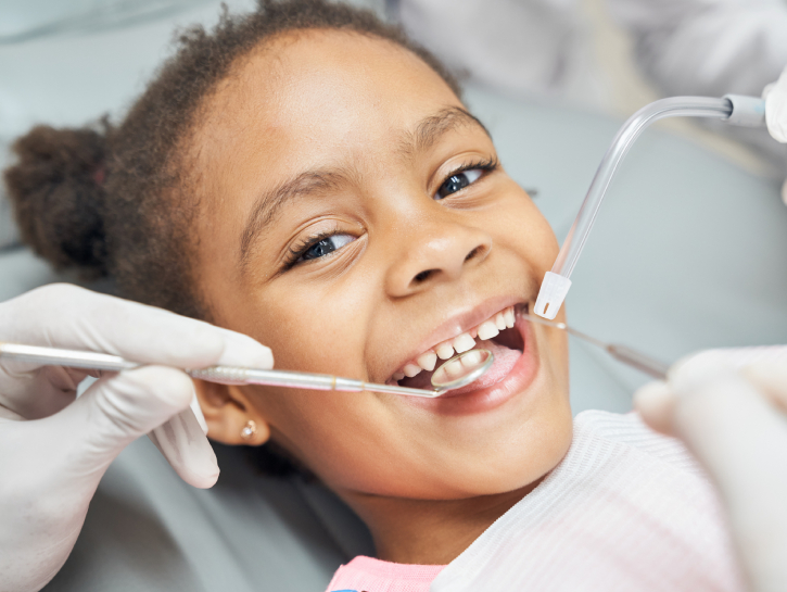 Young child receiving dental examination from dentist with tools in clinical setting.
