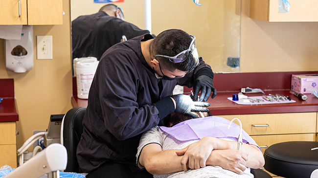 Dental professional examines young patient's teeth in clinical treatment room at Dove Family Dentistry.