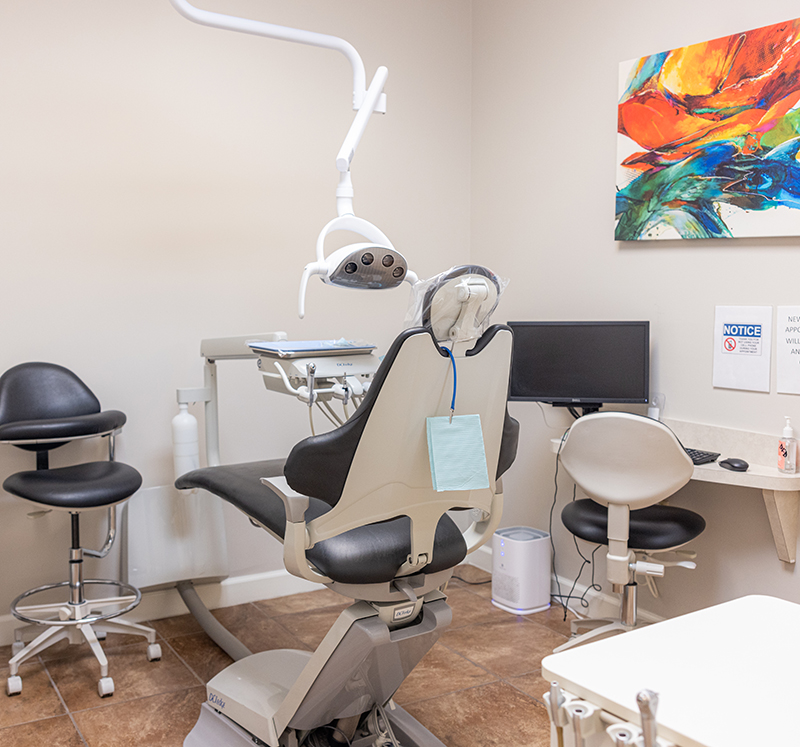 Modern dental treatment room with patient chair, overhead light, and sterilization equipment at Dove Family Dentistry.