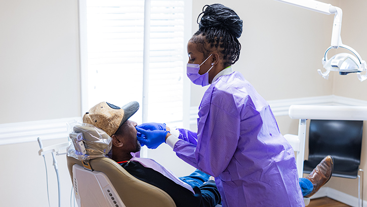 Dental professional in purple gloves examining patient in dental chair at Dove Family Dentistry clinic.