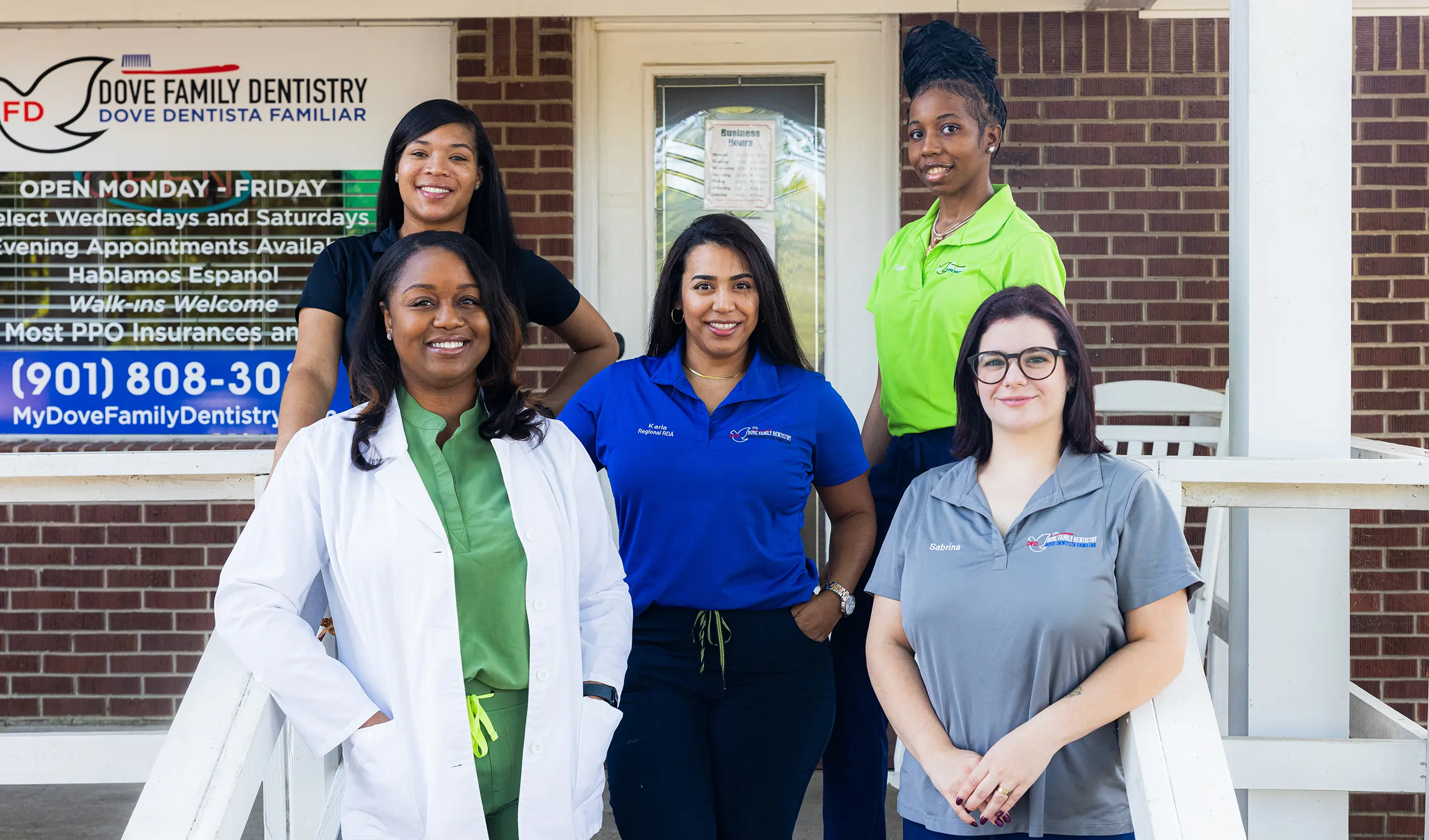 Dental team of five professionals posing together outside Dove Family Dentistry office building.