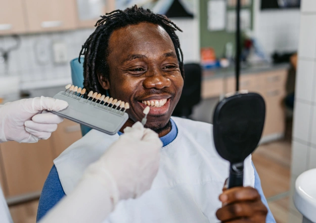 Smiling man holding dental tools in modern dental office setting.