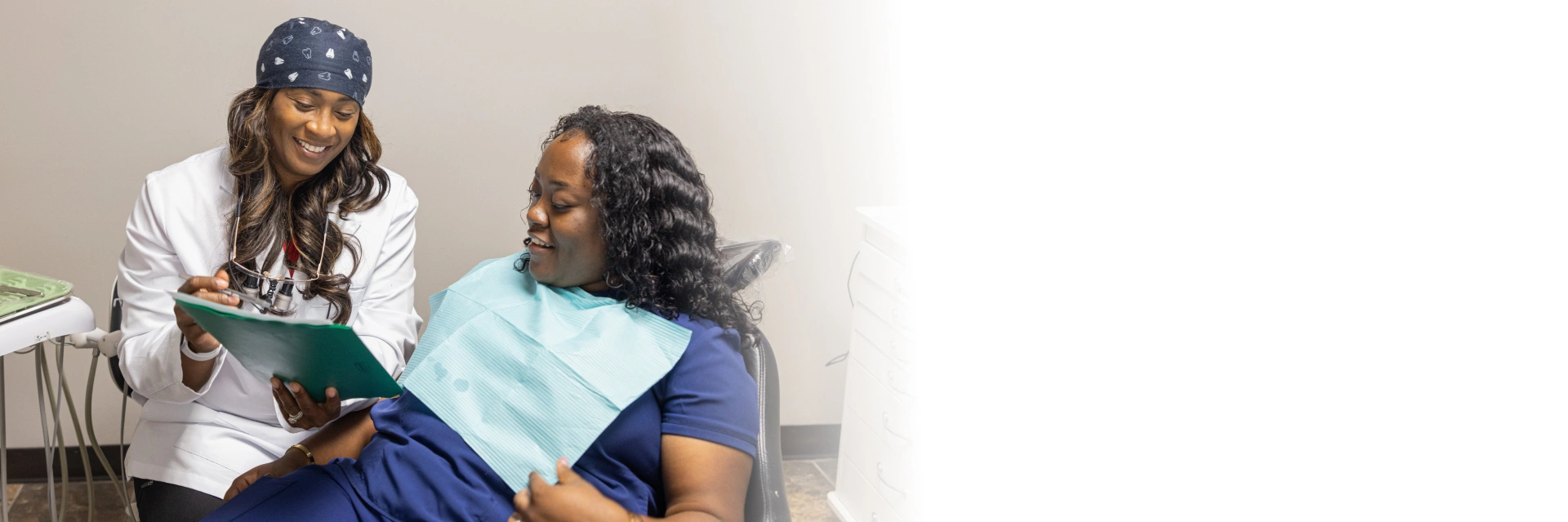 Dental hygienist showing patient X-rays during consultation in dental office examination room.