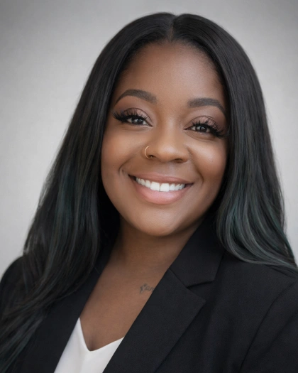 Professional headshot of smiling woman in black blazer against neutral background