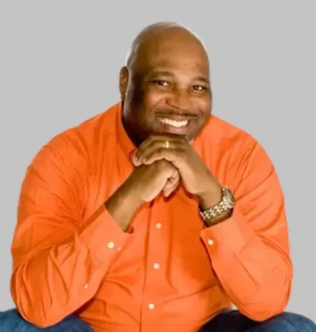 Dr. Christopher smiles warmly in an orange button-up shirt at Memphis dental practice.